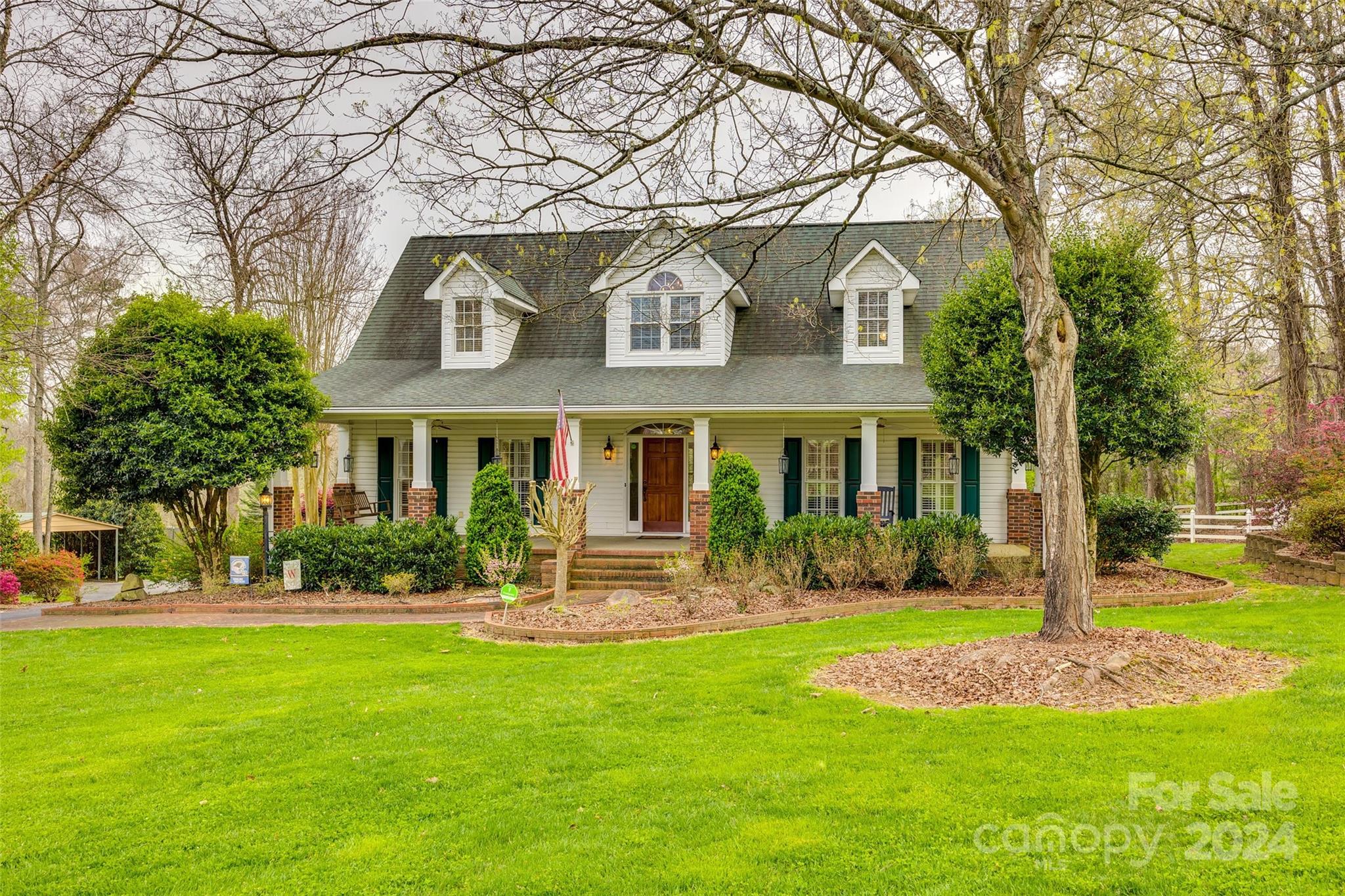 a front view of a house with garden and trees