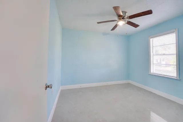 an empty room with a window and a fan