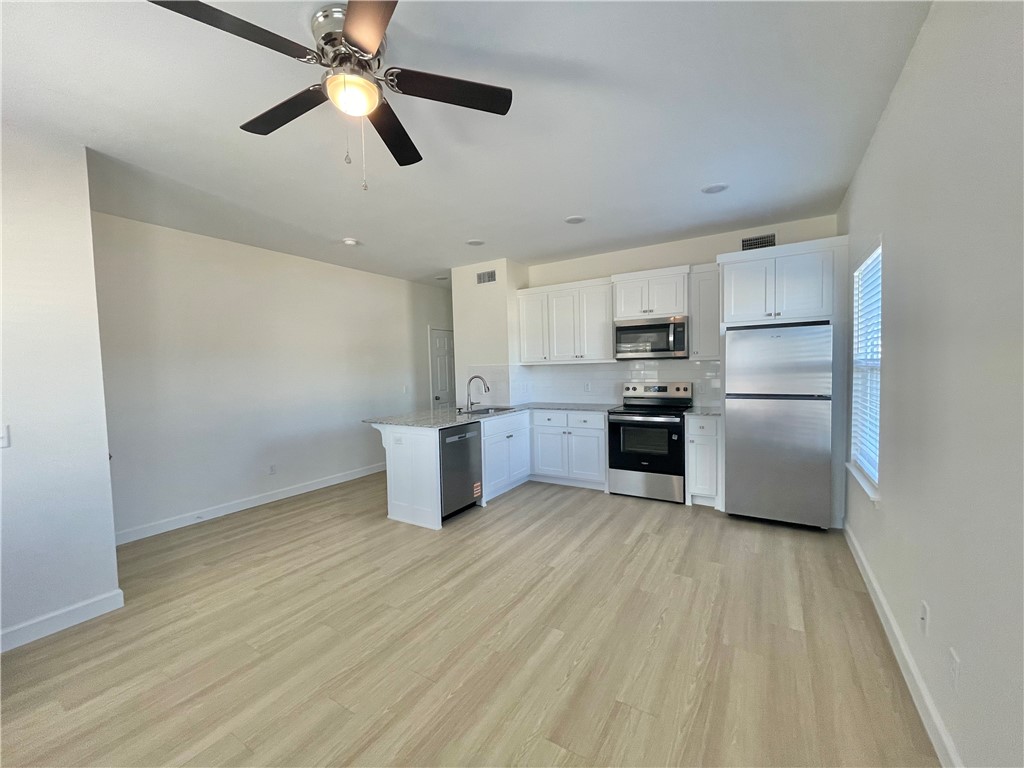 508 Park Street, Unit A Springdale, AR 72764 - Photo 3 of 7 Modern kitchen featuring white cabinetry, stainless steel appliances, and wood-finish flooring