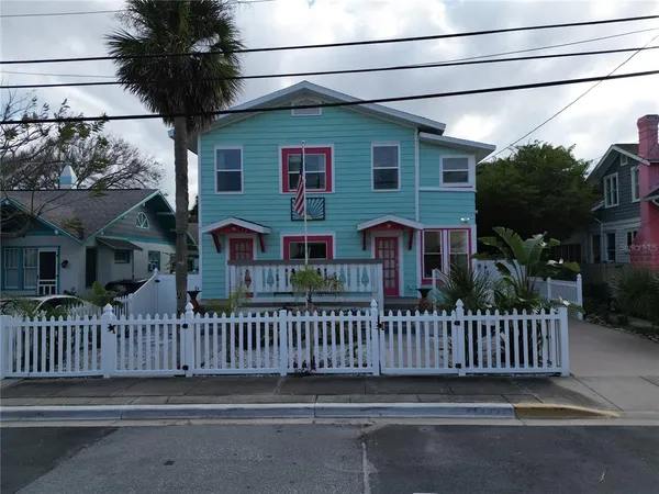 a view of a house with a small yard and wooden fence