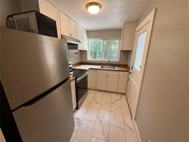 a kitchen with stainless steel appliances a refrigerator sink and microwave