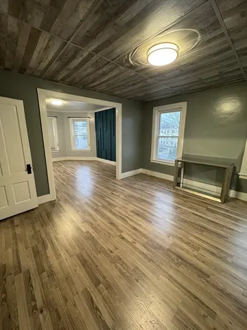 a view of an empty room with wooden floor and window