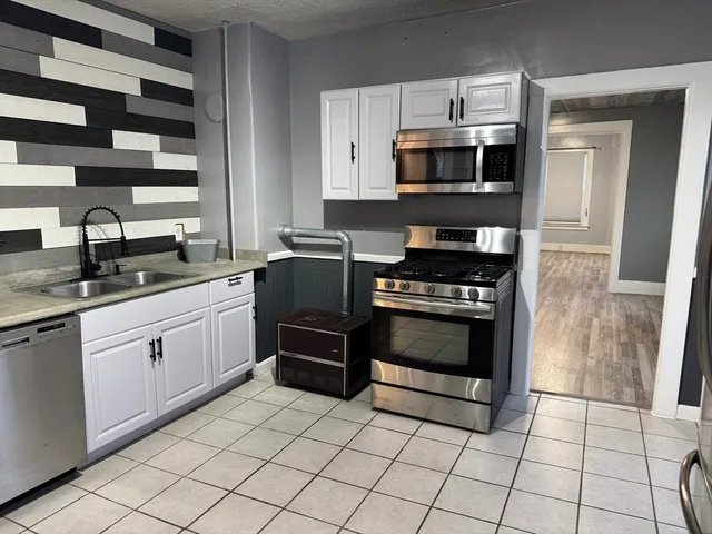 a kitchen with granite countertop a stove a sink and a microwave