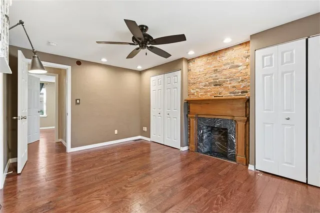 a view of a livingroom with wooden floor a ceiling fan and windows