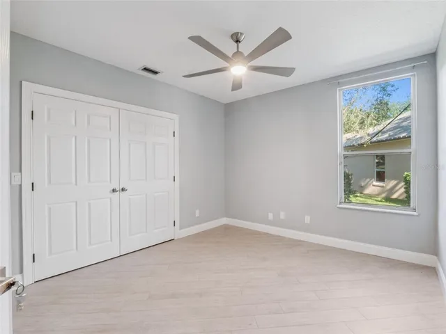 an empty room with windows and a ceiling fan