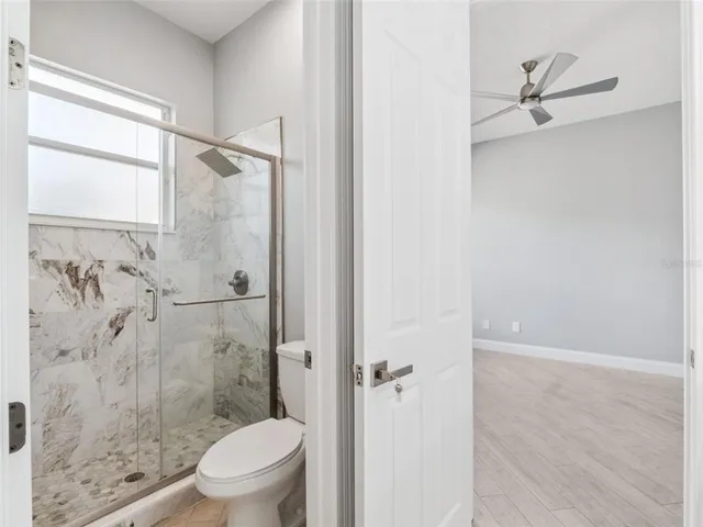 a bathroom with a granite countertop toilet a sink and shower