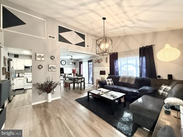 a living room with furniture kitchen view and a chandelier