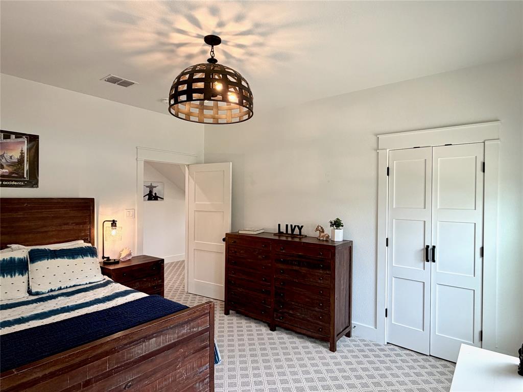 1304 Tinker Road Colleyville, TX 76034 - Photo 20 of 28 a bedroom with a bed and a chandelier