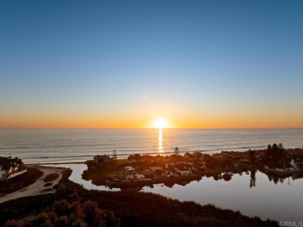an aerial view of ocean and residential houses with outdoor space