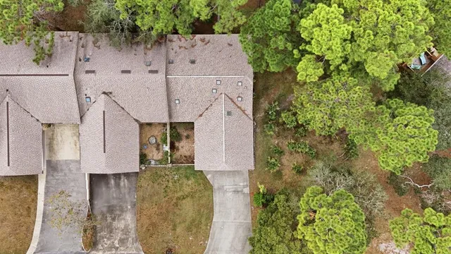 an aerial view of a house with a yard and trees all around