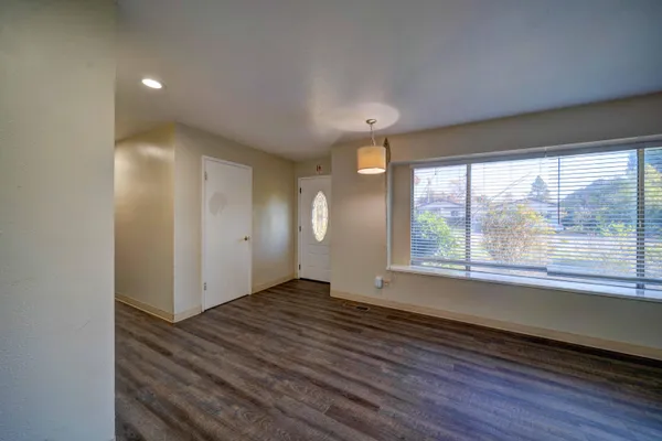 an empty room with wooden floor and windows