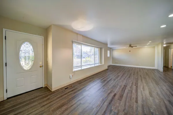 an empty room with wooden floor and windows