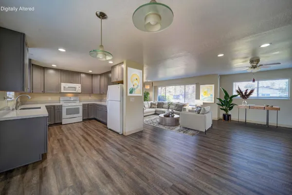 a living room with couches kitchen view and a chandelier