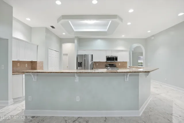 a view of a kitchen with kitchen island a sink stainless steel appliances and cabinets