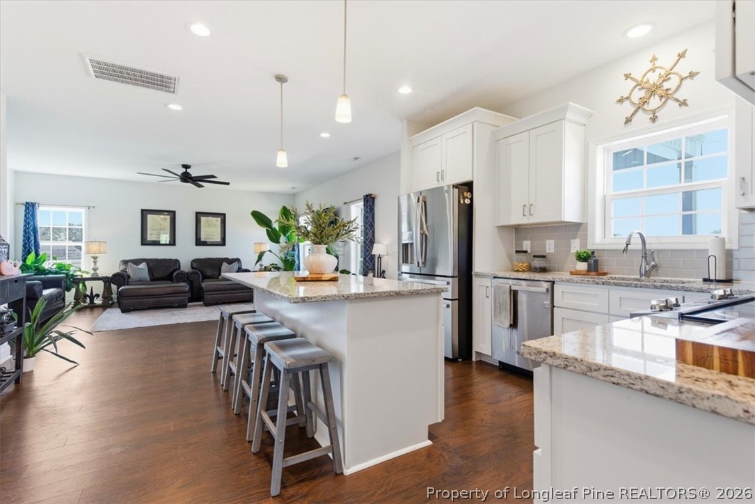 339 Rocking Horse Lane Raeford, NC 28376 - Photo 12 of 47 a kitchen with stainless steel appliances kitchen island granite countertop a refrigerator a sink a stove and chairs with wooden floor