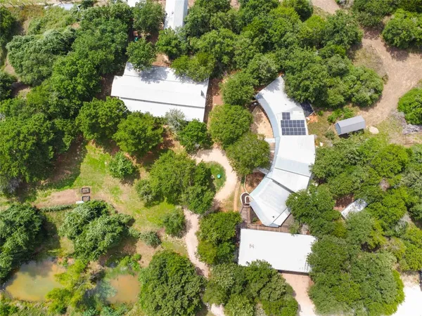 an aerial view of residential house with outdoor space and trees all around
