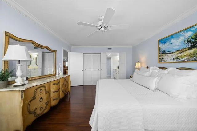 a spacious bedroom with a bed a dresser and potted plants on the dresser