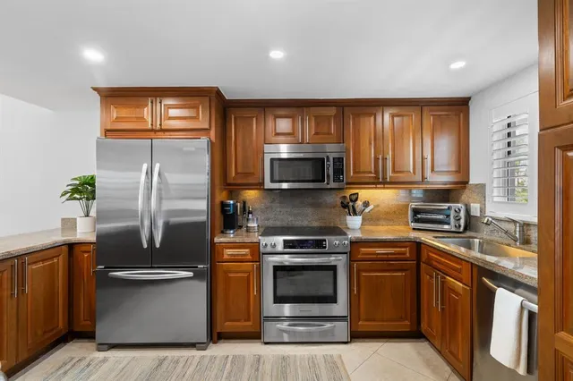 a kitchen with granite countertop a refrigerator stove and microwave