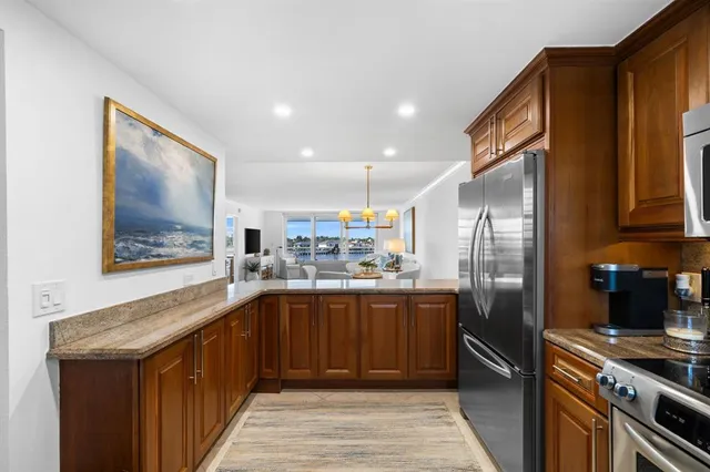 a kitchen with stainless steel appliances granite countertop a refrigerator a sink dishwasher and wooden cabinets with wooden floor