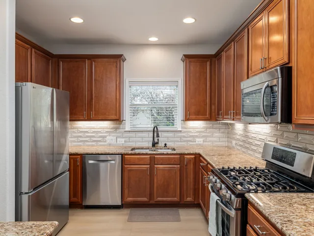 a kitchen with granite countertop stainless steel appliances a sink stove and refrigerator