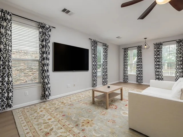 a living room with furniture a flat screen tv and a large window