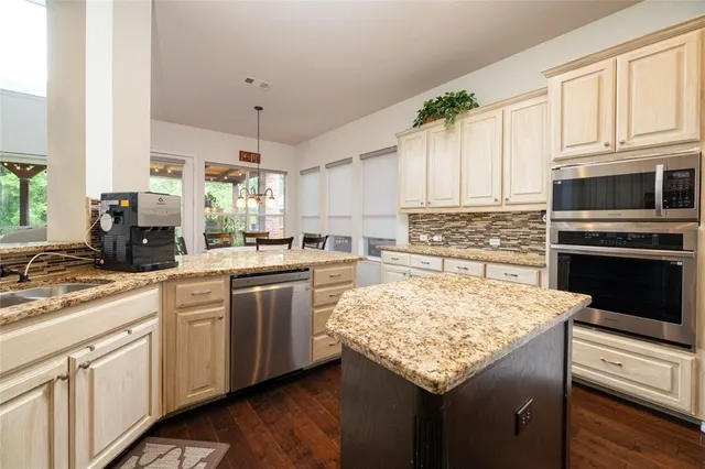 a kitchen with stainless steel appliances kitchen island granite countertop a stove sink and cabinets