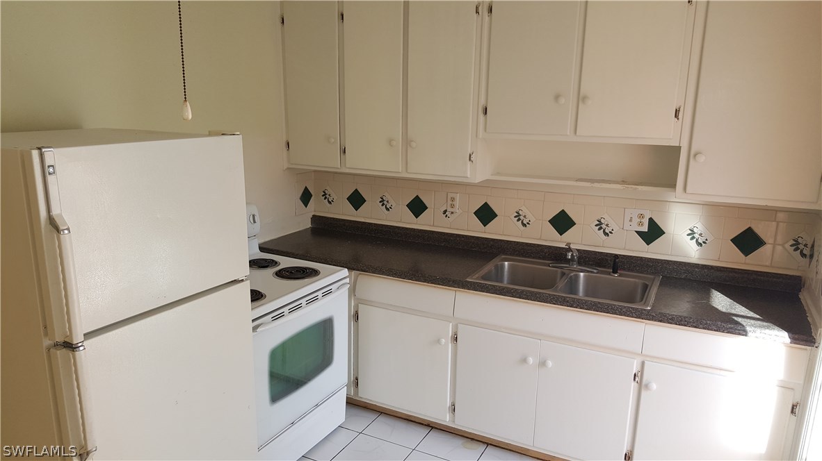 1924 Coronado Road Fort Myers, FL 33901 - Photo 7 of 11 a kitchen with white cabinets and white appliances