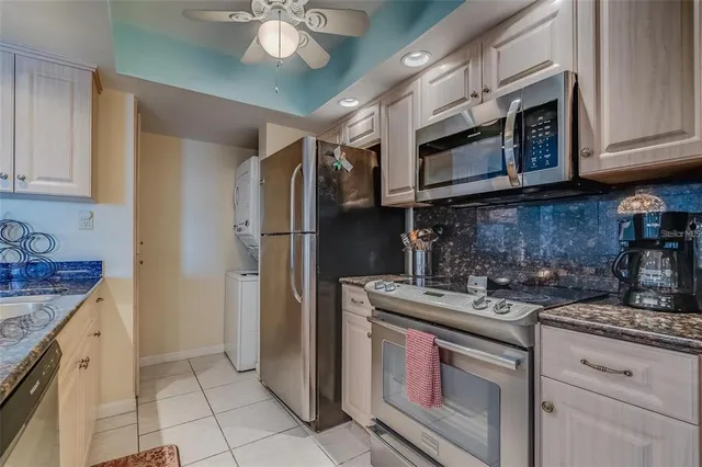 a kitchen with stainless steel appliances granite countertop a refrigerator a stove and a sink