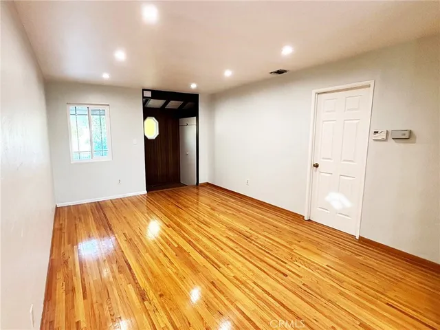 a view of an empty room and window and wooden floor