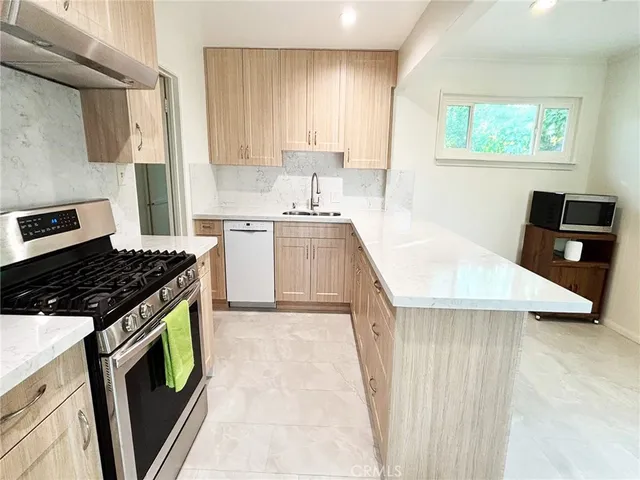 a kitchen with stainless steel appliances granite countertop a stove a sink and a microwave