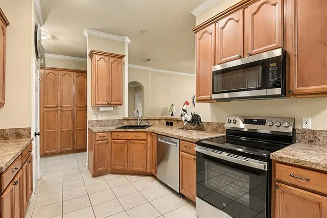 a kitchen with stainless steel appliances granite countertop a sink a stove and a refrigerator with wooden cabinets