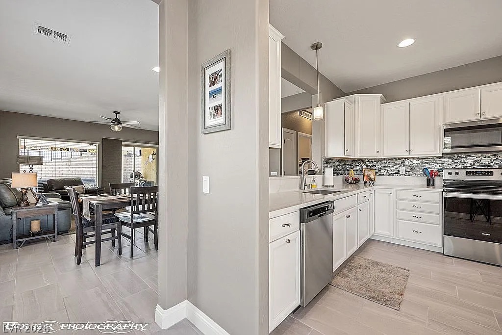 1304 Cottage Ridge Mesquite, NV 89034 - Photo 7 of 52 A sleek, contemporary kitchen with pristine white cabinetry and stainless steel appliances seamlessly transitions to the dining area.