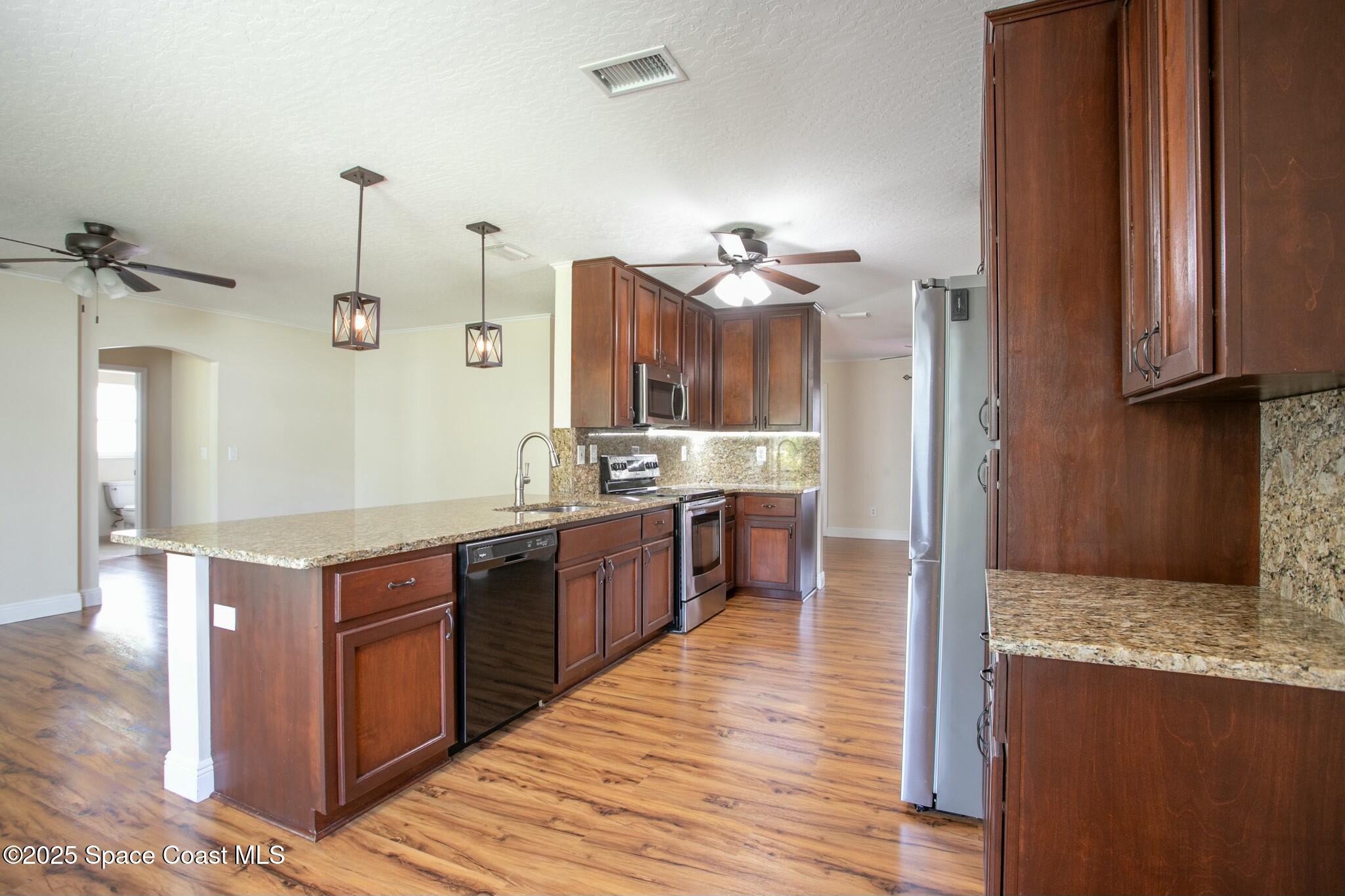 6485 Orchid Avenue Cocoa, FL 32927 - Photo 11 of 24 a kitchen with stainless steel appliances granite countertop a sink a stove and a wooden floors