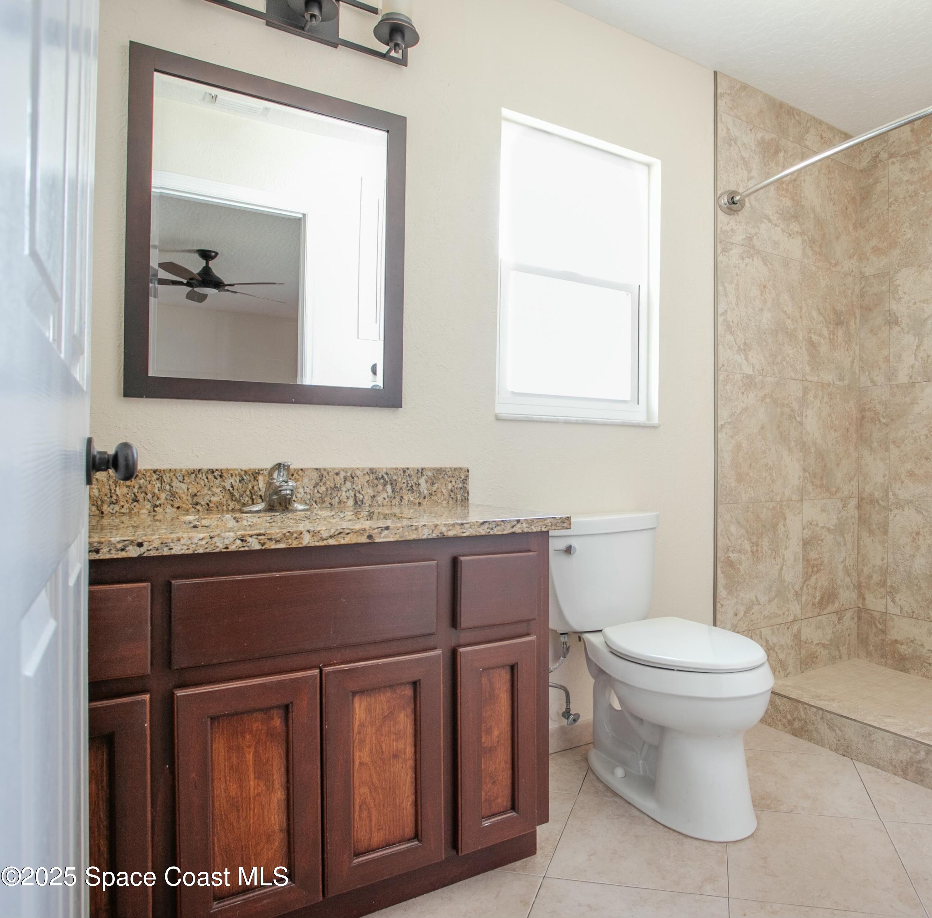 6485 Orchid Avenue Cocoa, FL 32927 - Photo 16 of 24 a bathroom with a granite countertop toilet sink and mirror