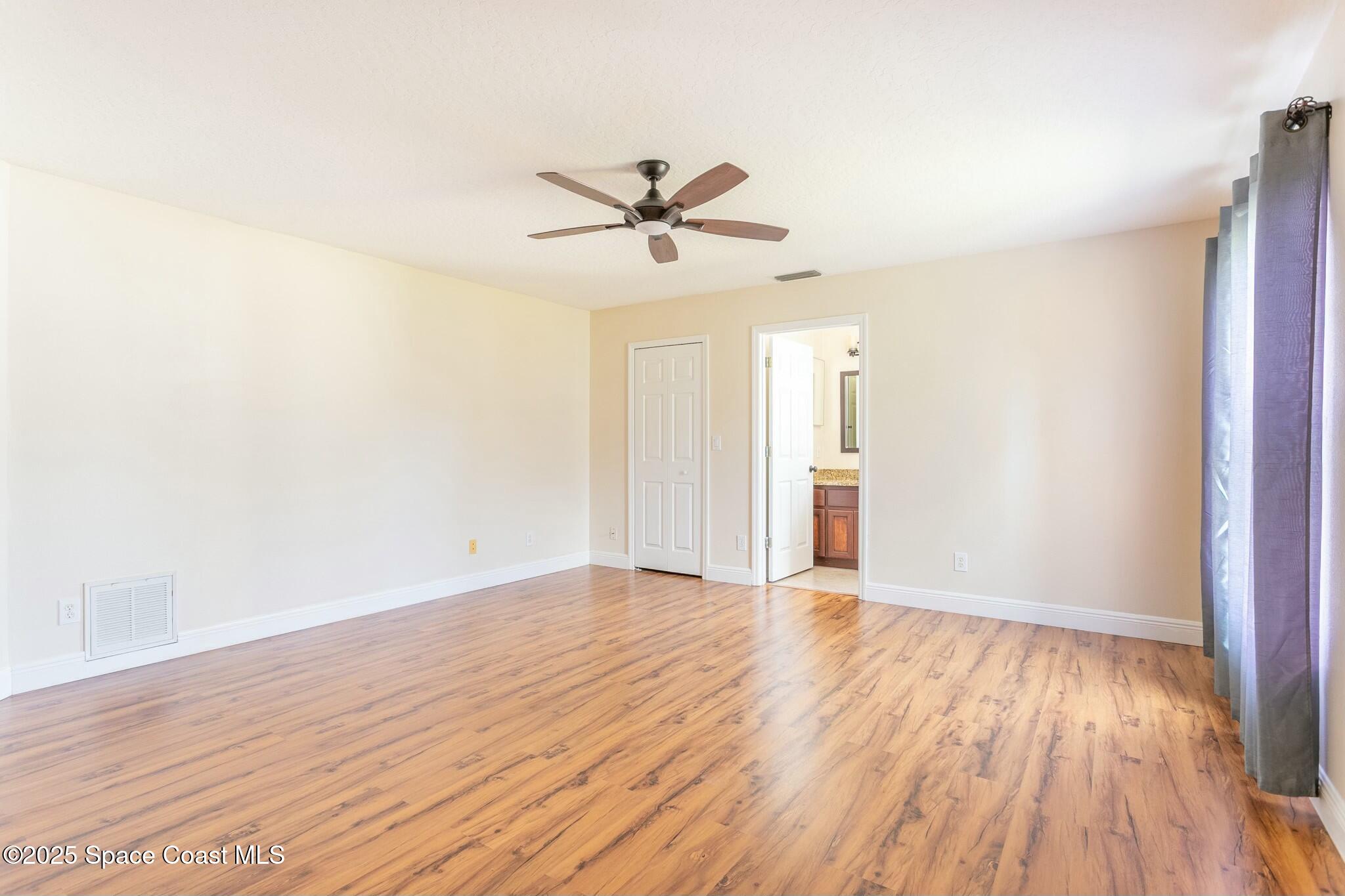6485 Orchid Avenue Cocoa, FL 32927 - Photo 17 of 24 an empty room with wooden floor ceiling fan and windows