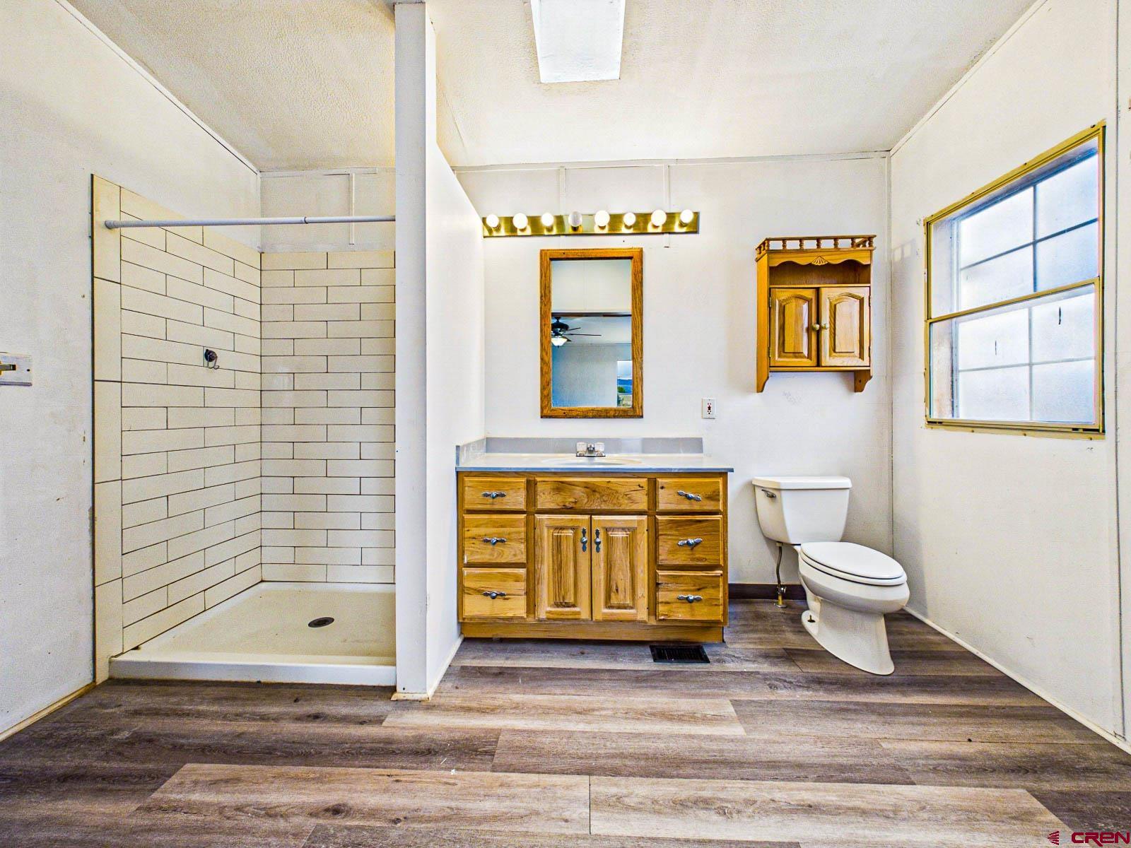 15484 Peach Road Cedaredge, CO 81413 - Photo 20 of 35 a bathroom with a granite countertop sink toilet and shower