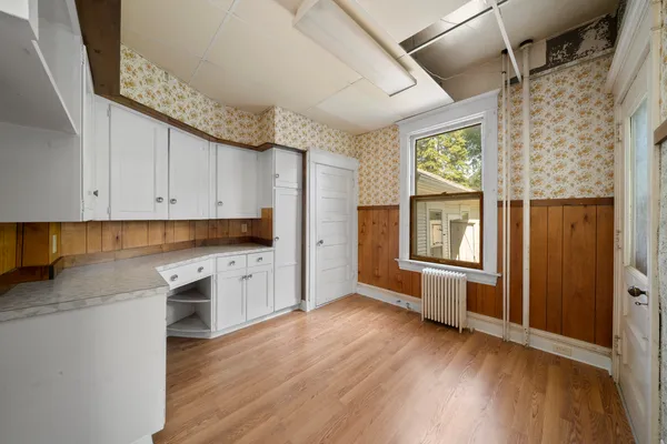 a kitchen with granite countertop white cabinets and wooden floor
