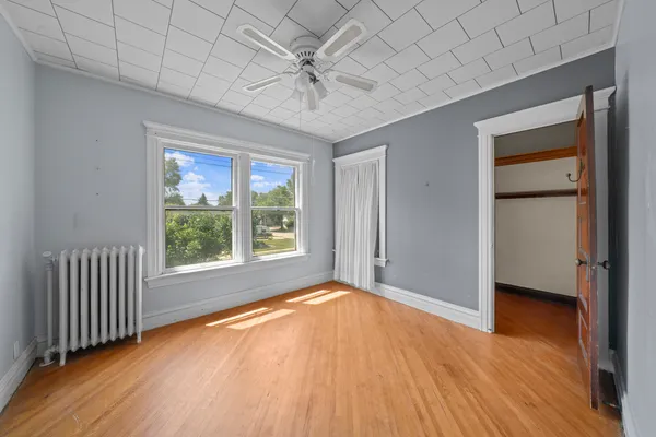 a view of an empty room with a window and wooden floor