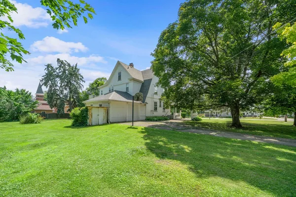 a view of a house with a big yard and a large tree