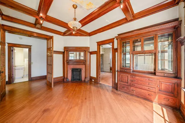 a view of an empty room with wooden floor and a fireplace