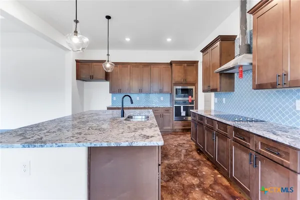 a kitchen with stainless steel appliances granite countertop a sink stove and cabinets