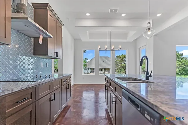 a large kitchen with stainless steel appliances a sink and a wooden floor