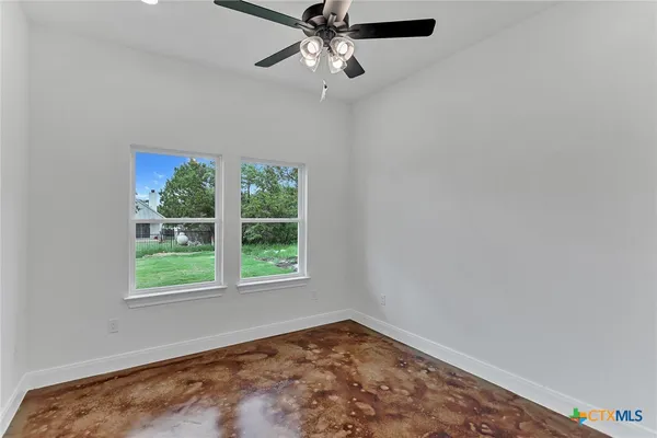 an empty room with a window and ceiling fan