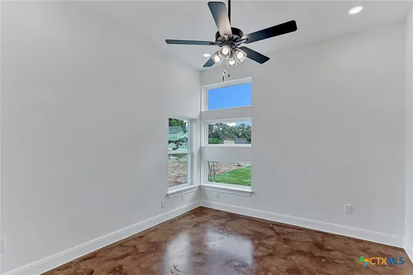 an empty room with windows and fan