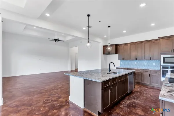 a kitchen with a sink a counter top space appliances and cabinets