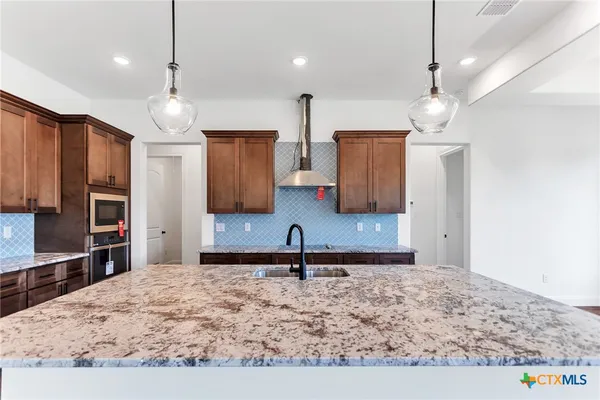 a kitchen with stainless steel appliances granite countertop a sink refrigerator and cabinets