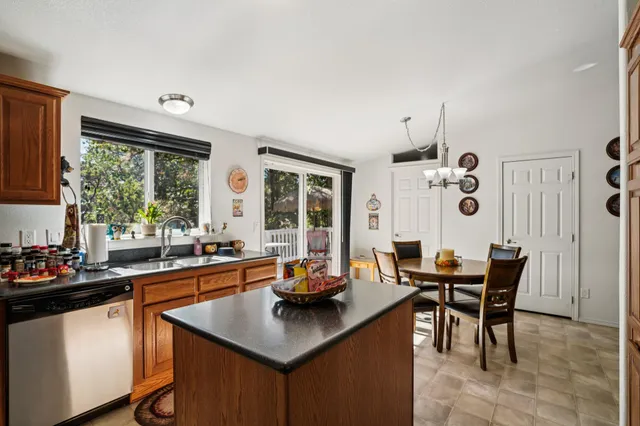 a kitchen with stainless steel appliances granite countertop a sink dishwasher and a refrigerator with wooden cabinets