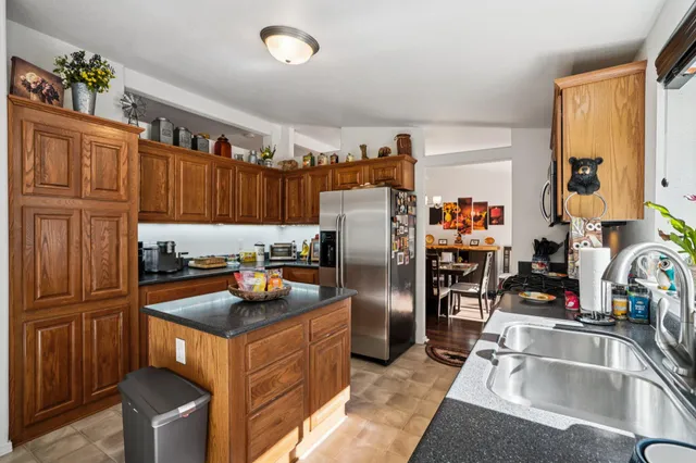 a kitchen with granite countertop stainless steel appliances a sink stove refrigerator and a window