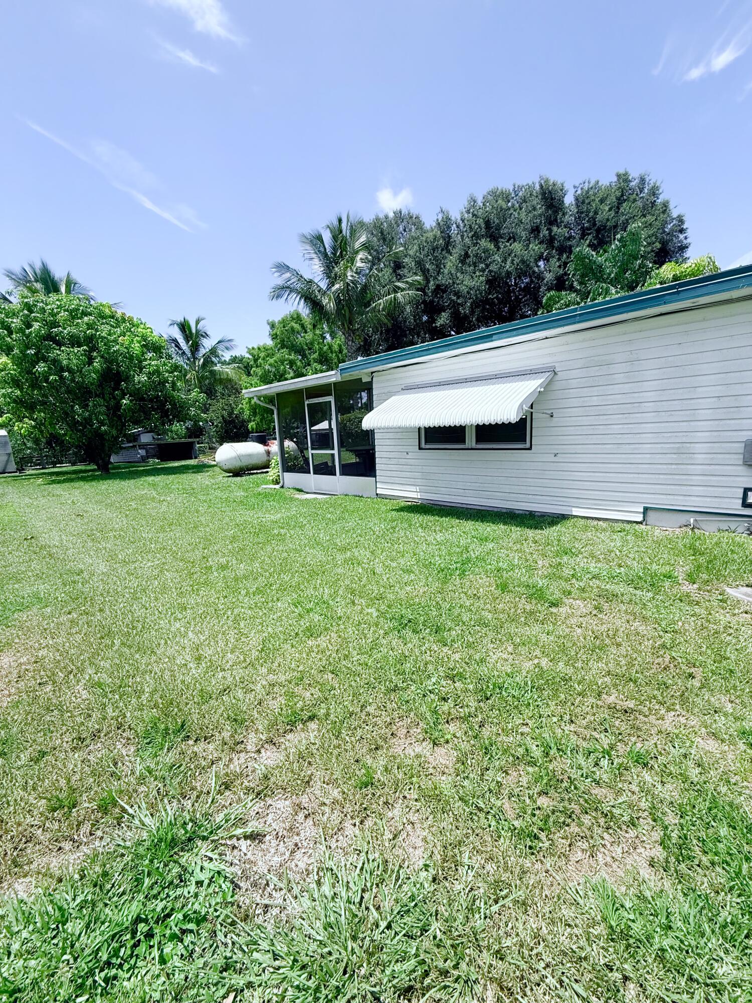1736 Hunter Road Okeechobee, FL 34974 - Photo 27 of 35 a backyard of a house with plants and large tree