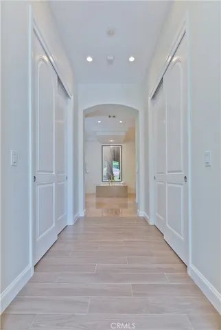 a view of a hallway to a bedroom with wooden floor and windows